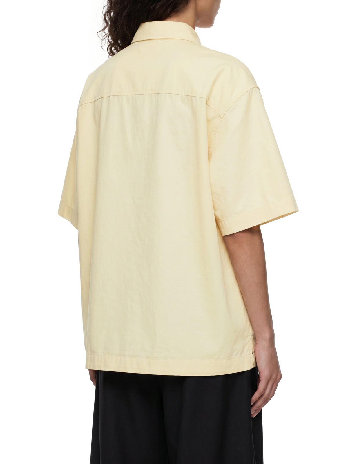 Back view of the Unisex Resist 100% Cotton Oversized Drop-Shoulder Short Sleeve Shirt With Patch Pocket in light cream, modeled with a relaxed oversized fit